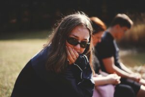 Person sitting distanced in social interaction looking tired and overwhelmed, representing exhaustion socialising - Anxiety Therapy UK