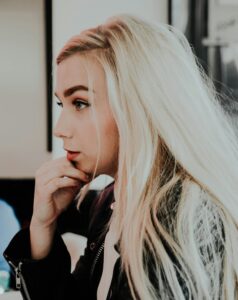A thoughtful blonde woman sat surrounded by her thoughts and looking overwhelmed as she struggles to start everyday tasks, representing ADHD task paralysis and executive dysfunction.