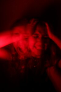 Woman sitting with her head in her hands while colourful emotions surround her, representing emotional regulation challenges in adults with ADHD.