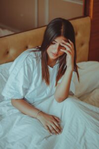 Woman sat awake in bed overthinking, representing anxiety, OCD, guilt and replaying conversations.