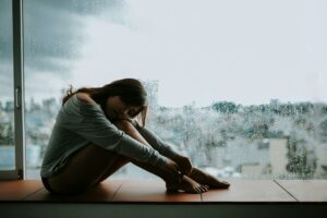 Person reflecting alone, representing losing yourself in a relationship, people pleasing, attachment and rebuilding your sense of identity.